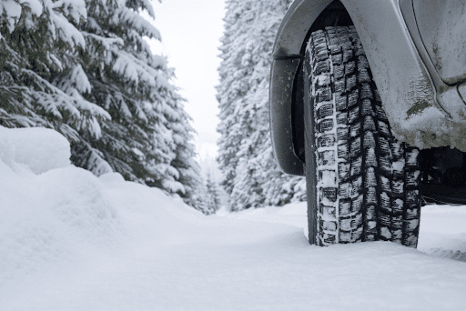 Winter Tires in Seekonk: A car equipped with winter tires driving safely on a snowy road, emphasizing the importance of proper tire choice for winter conditions by Trustworthy Auto.