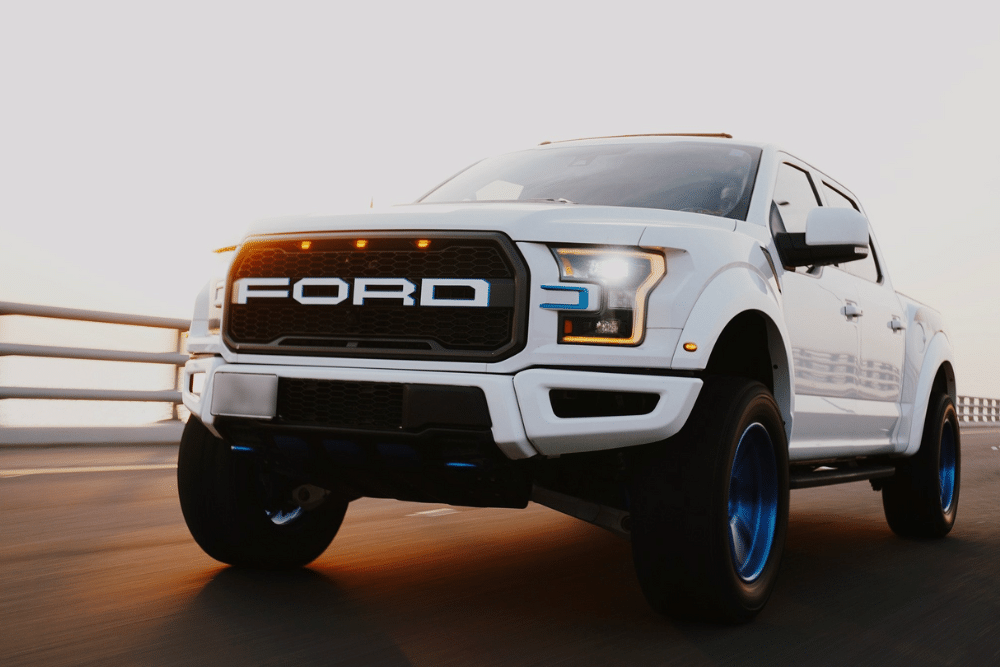 lincoln & ford repair, auto repair in Seekonk, MA at Trustworthy Auto. Auto. Image of a white Ford truck driving on a highway at sunset, emphasizing rust protection and long-term vehicle durability.
