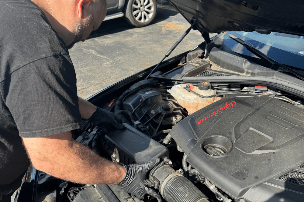 engine maintenance, auto repair in Seekonk, MA at Trustworthy Auto. Auto. Image of a mechanic inspecting a car engine bay outdoors, highlighting professional troubleshooting and performance care.