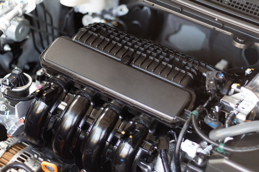 engine maintenance, auto repair in Seekonk, MA at Trustworthy Auto. Close-up of a clean car engine bay showing black intake manifold and engine cover components.